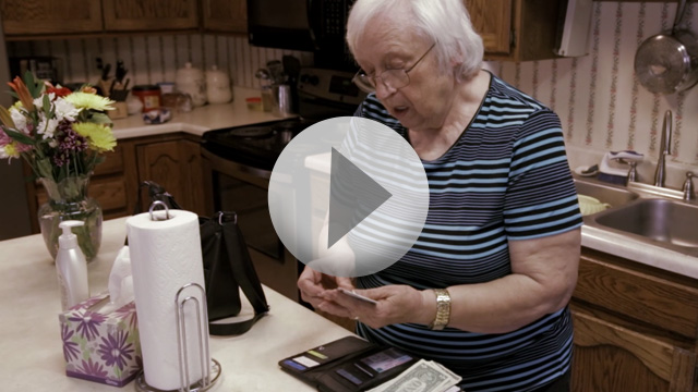 Older woman in her kitchen looking through wallet contents